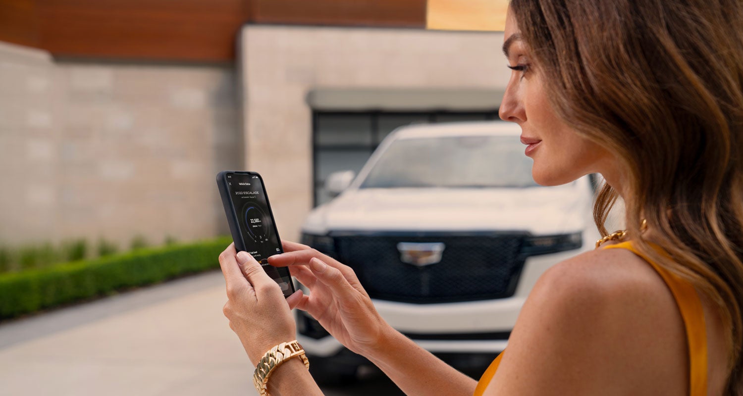 lady checking her mobile with a Cadillac vehicle background | Cadillac of Memphis in Memphis TN